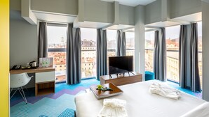 A hotel room with a large bed, a desk, a TV, and a view of the city. - Ibis Styles Lviv Center (Lviv)
