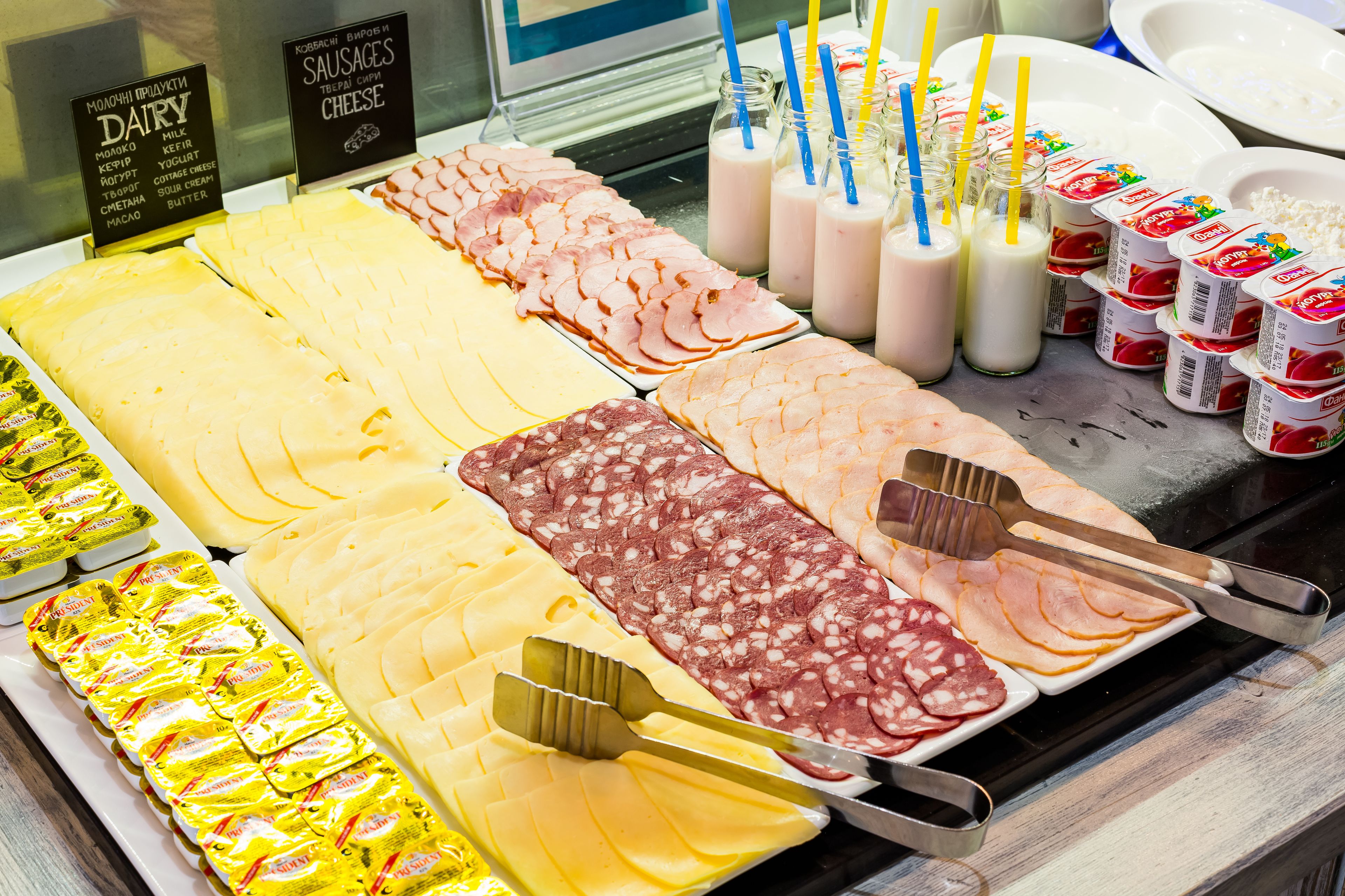 A deli counter with various cheeses, meats, and dairy products.