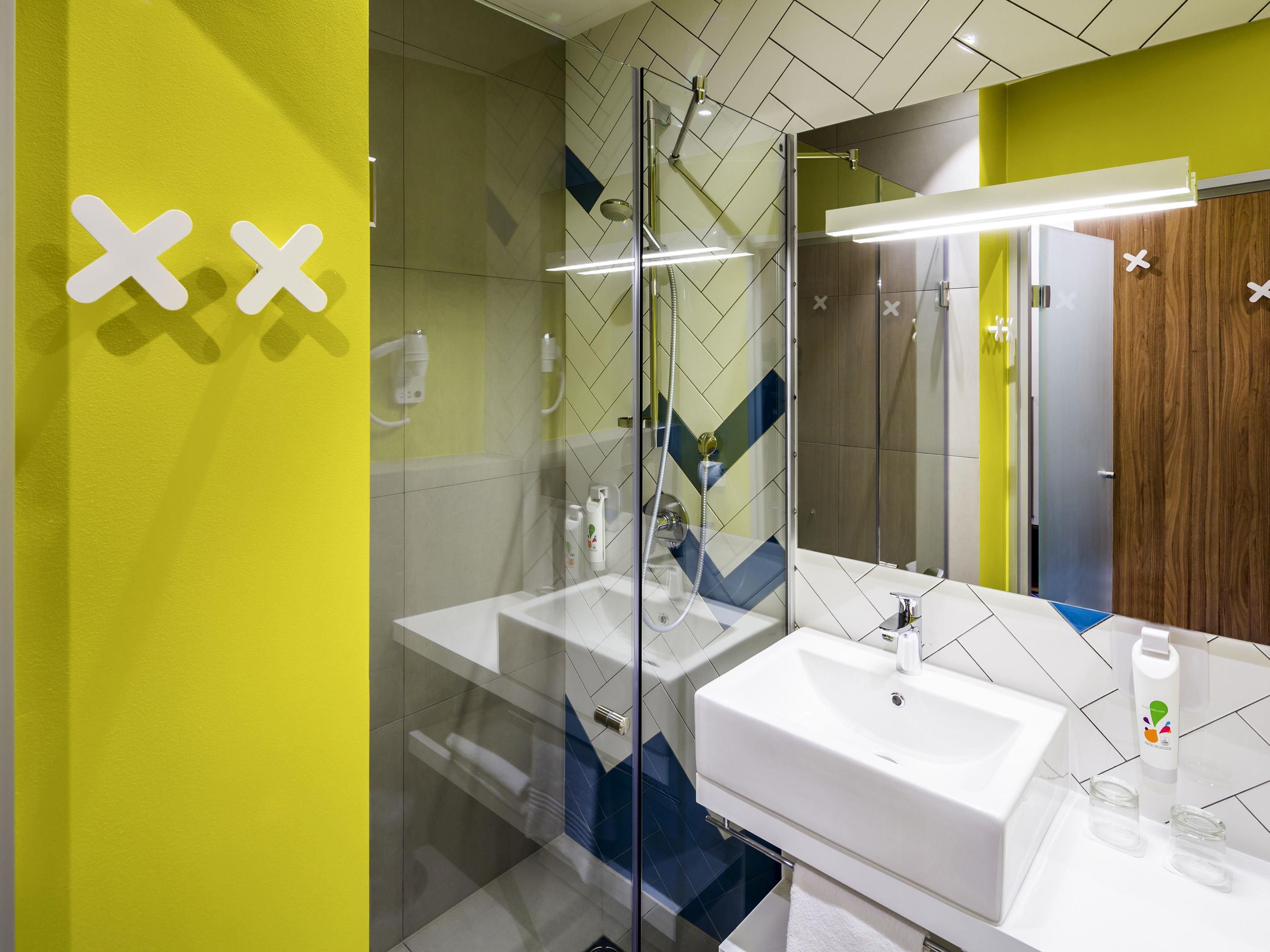 A modern bathroom with a glass-enclosed shower, a white sink, and a mirror.