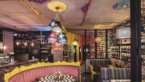 A bar area with a checkered table, seating with striped cushions, and shelves with bottles. - Ibis Styles Lviv Center (Lviv)