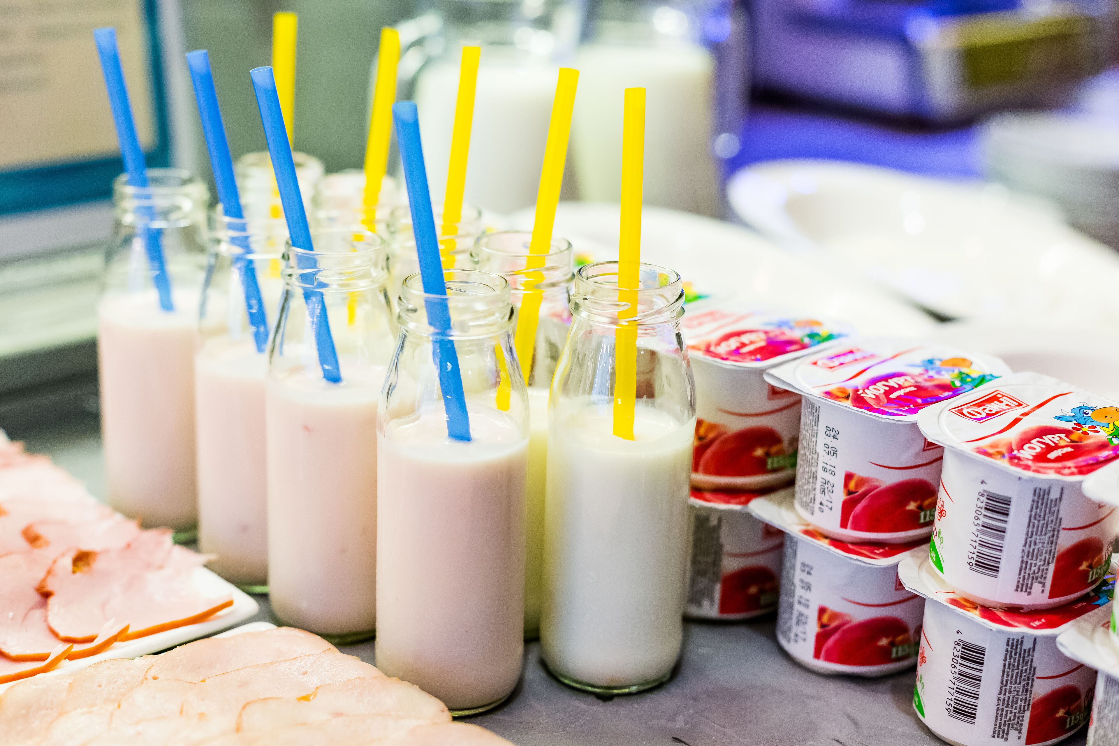A display of milkshakes and yogurt cups with straws.