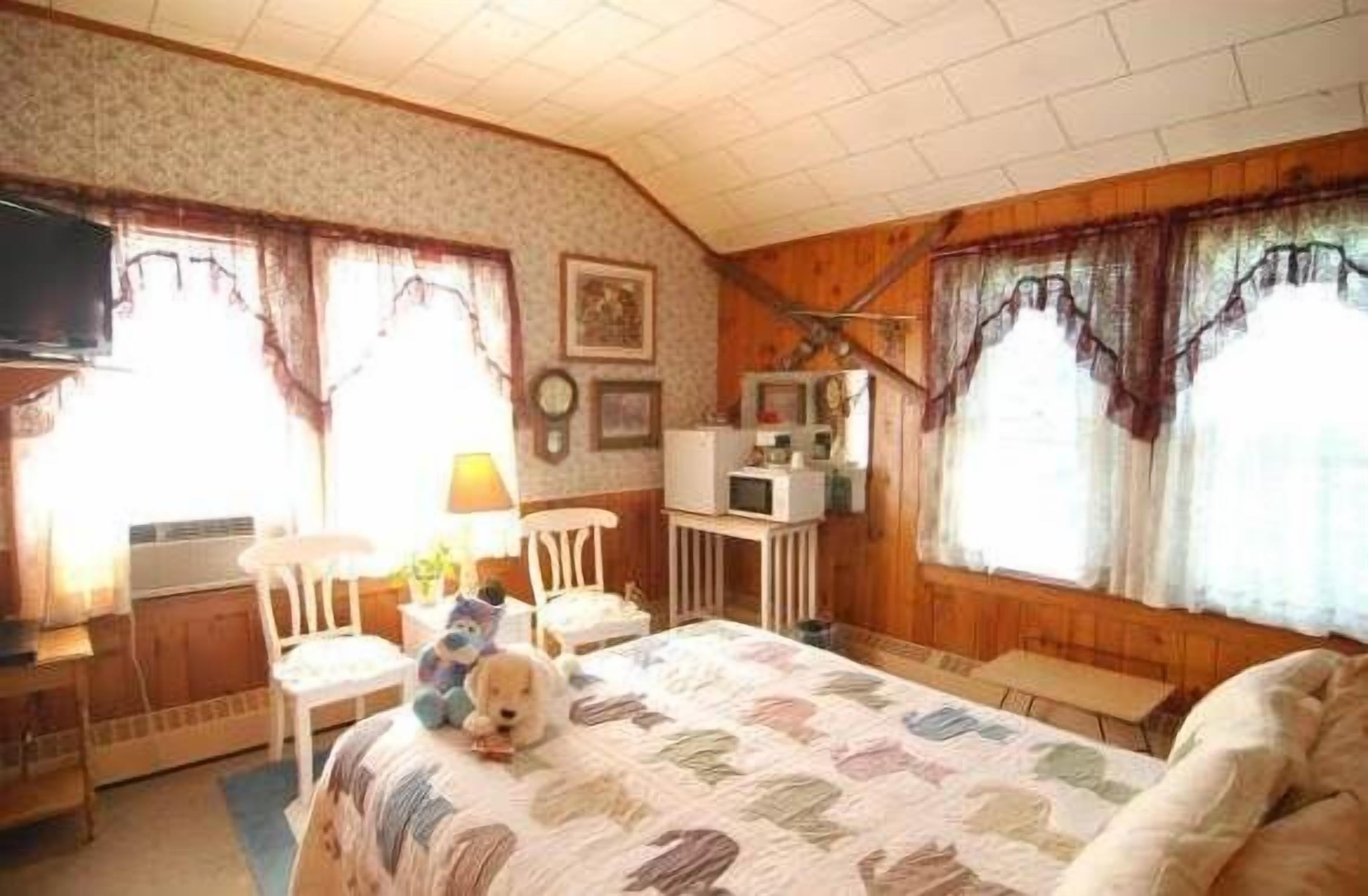 A cozy room with a bed, a desk, a chair, and a television.