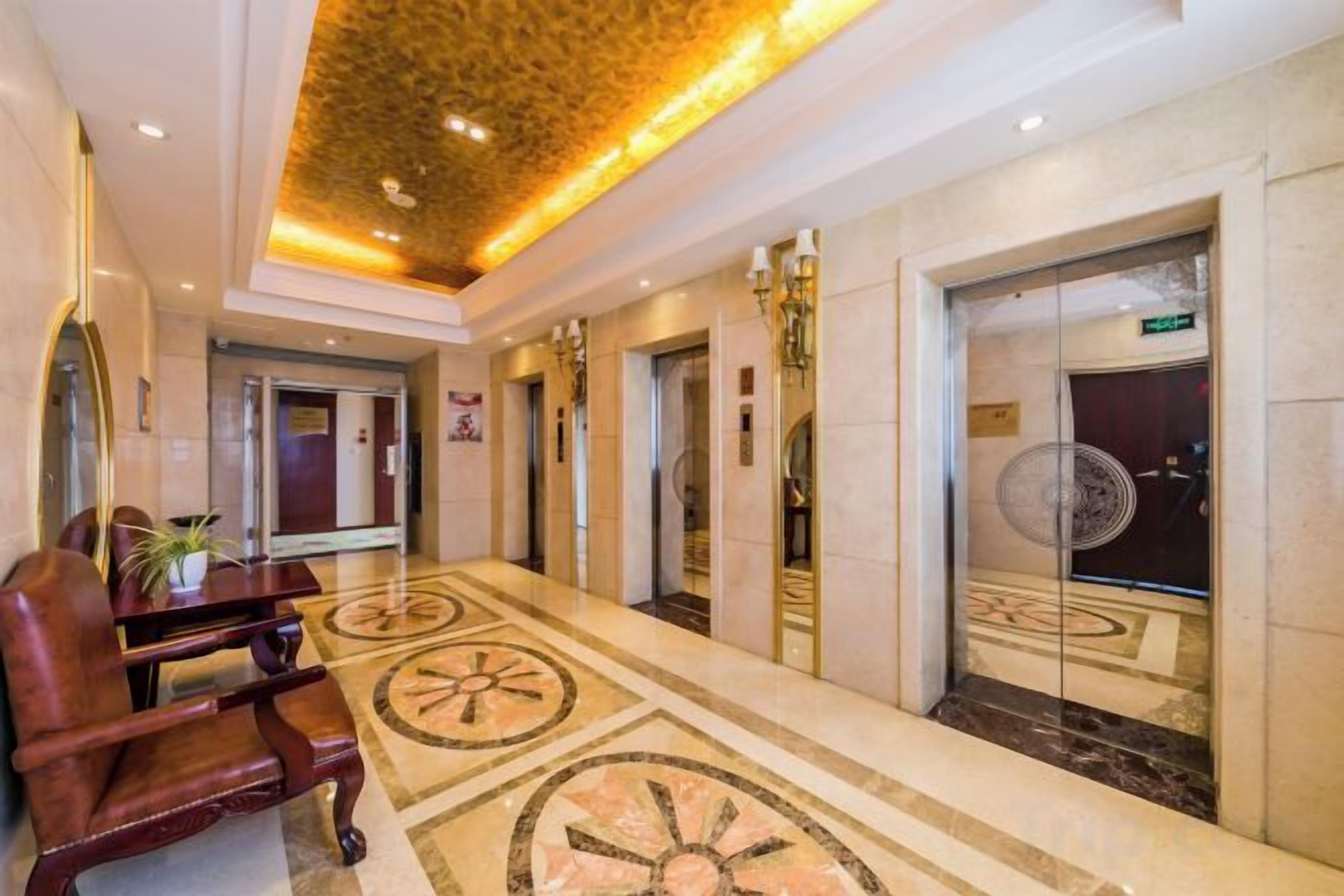 A hotel lobby with a marble floor, a reception desk, and a seating area.