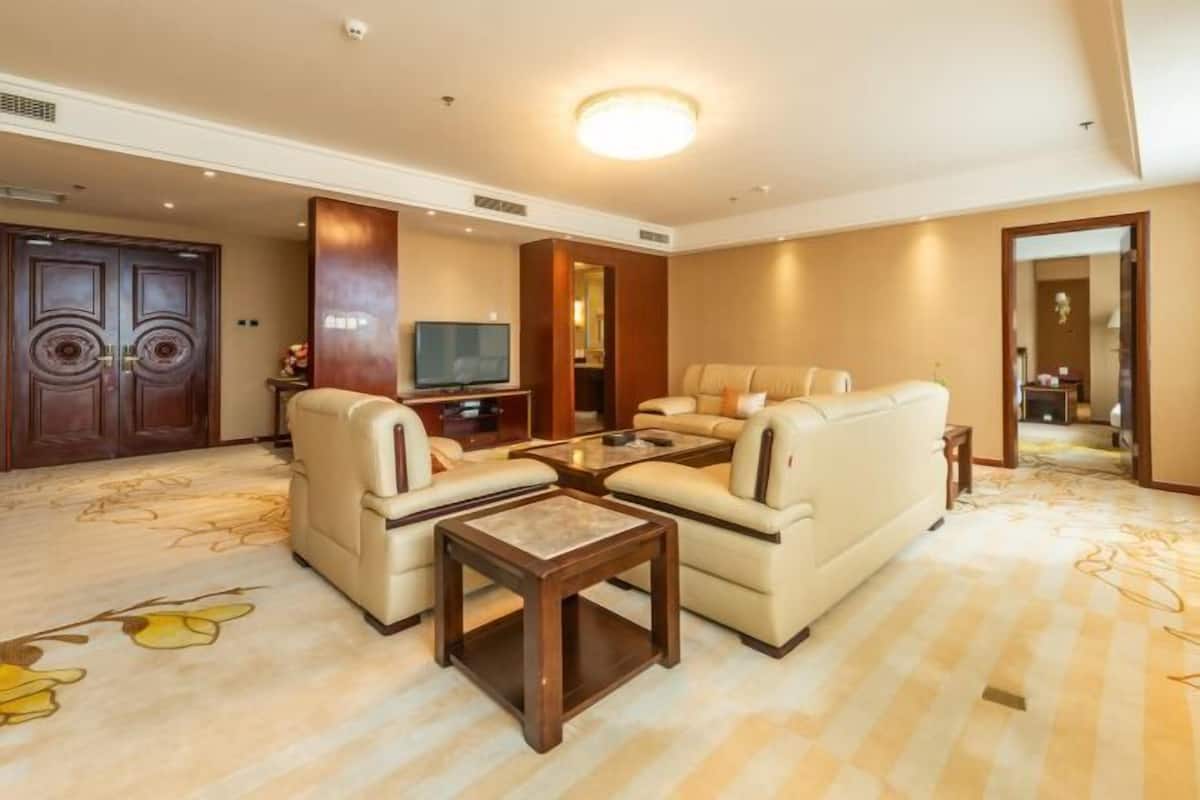 Uma sala de estar ampla, com sofás, uma mesa de centro e uma televisão.