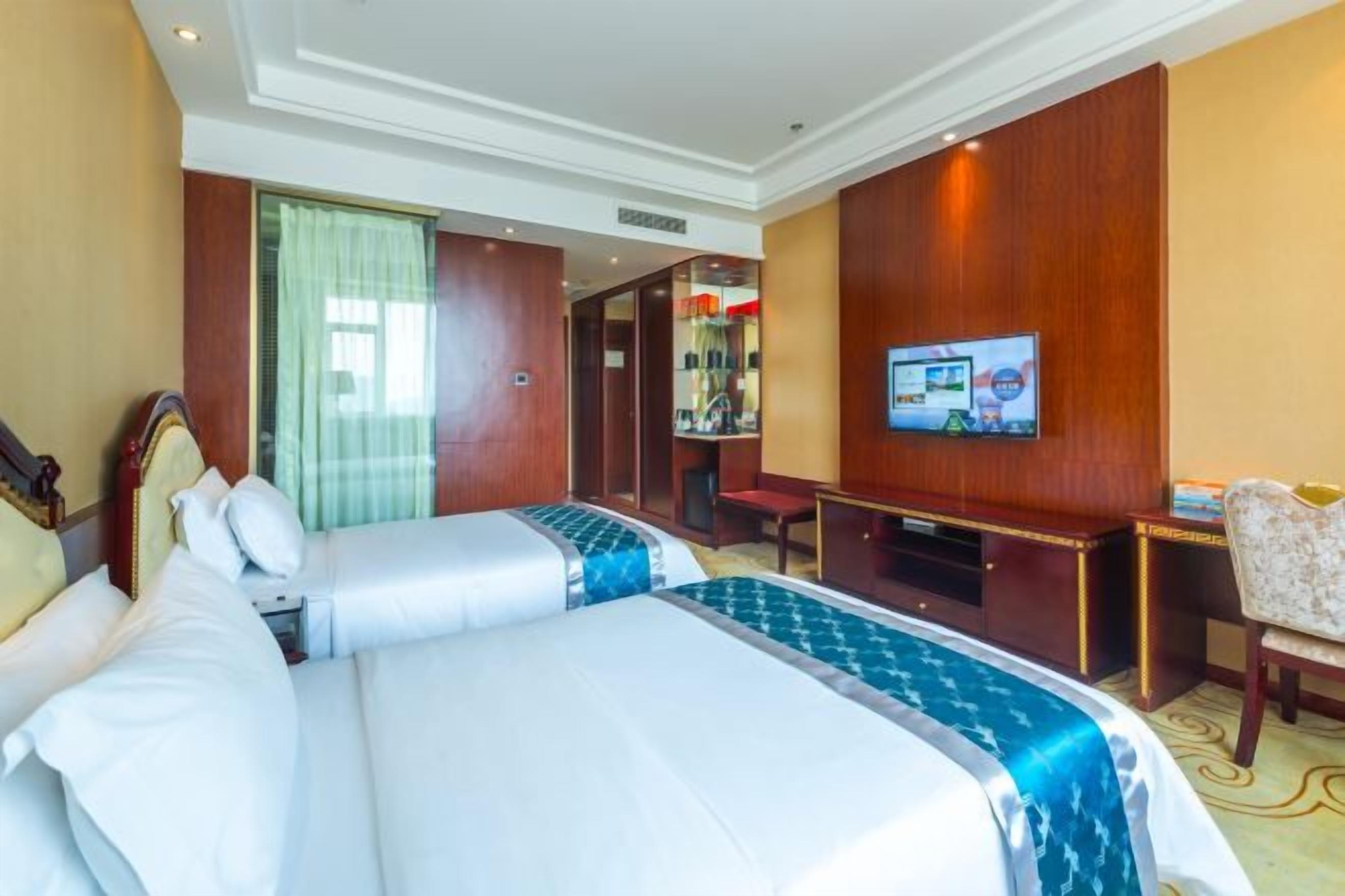 Habitación de hotel con dos camas, televisión, escritorio y una silla.