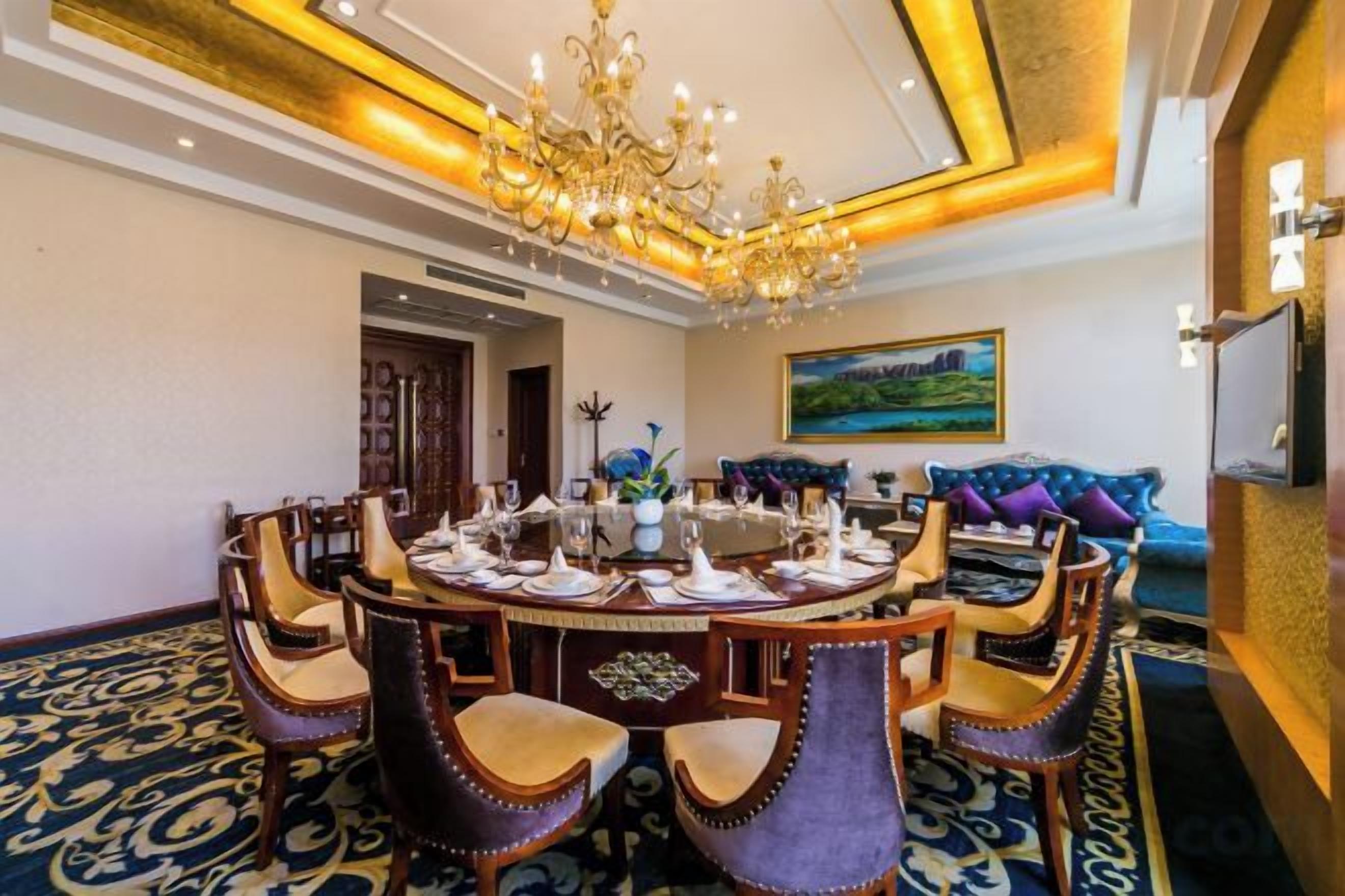 Un comedor formal con una mesa redonda, sillas ornamentadas y una araña.