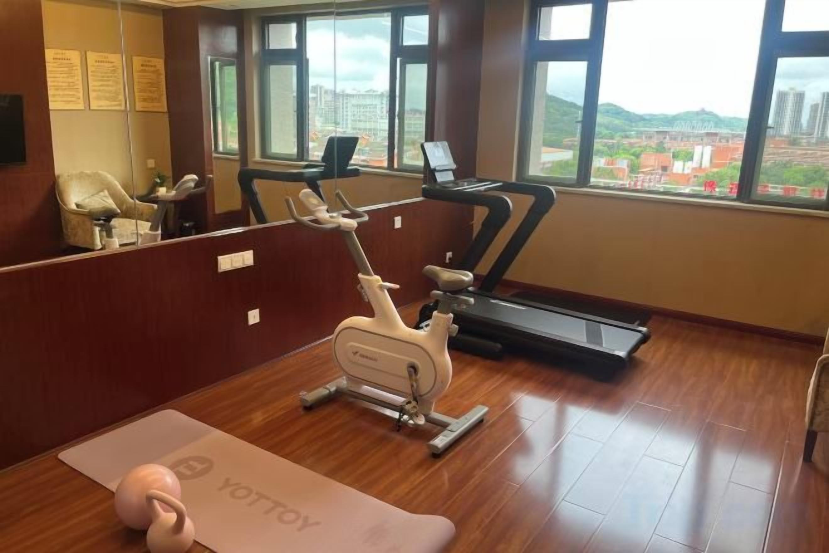 Un gimnasio con equipo de ejercicio, una cinta de correr y una esterilla de yoga.