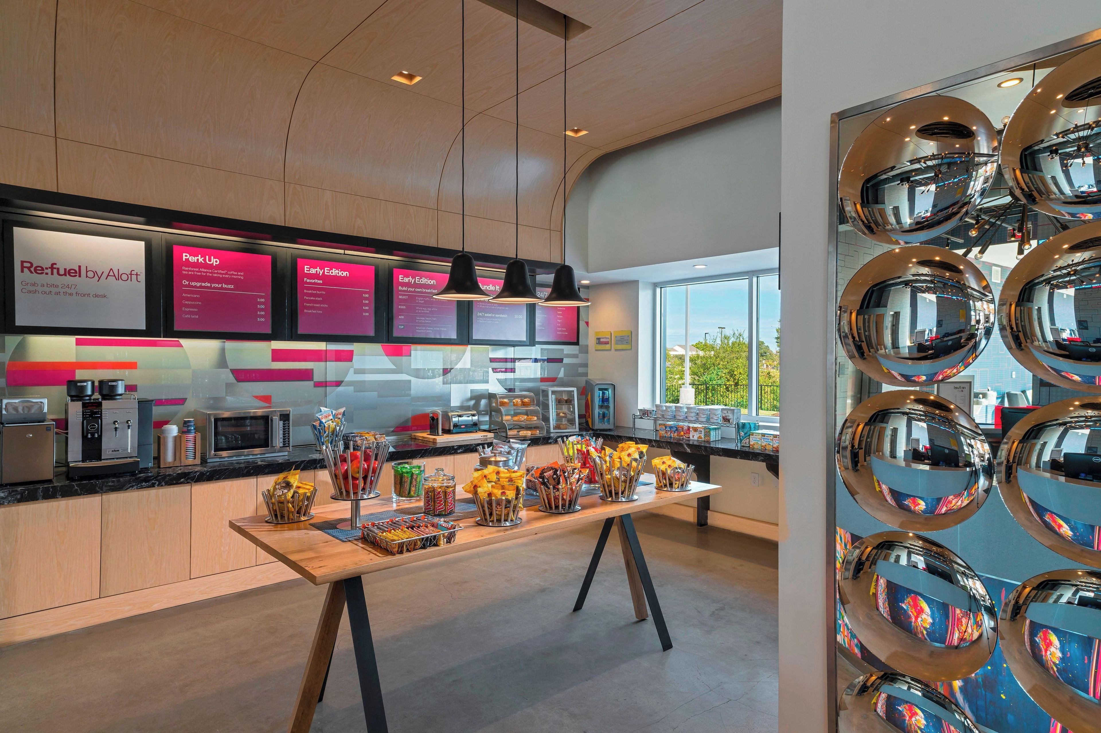 A modern coffee shop interior with a wooden counter, espresso machines, and a variety of snacks.