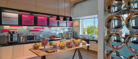 A modern coffee shop interior with a wooden counter, espresso machines, and a variety of snacks.