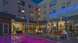 A modern hotel with a rooftop pool area featuring lounge chairs and umbrellas. - Aloft by Marriott College Station (College Station)