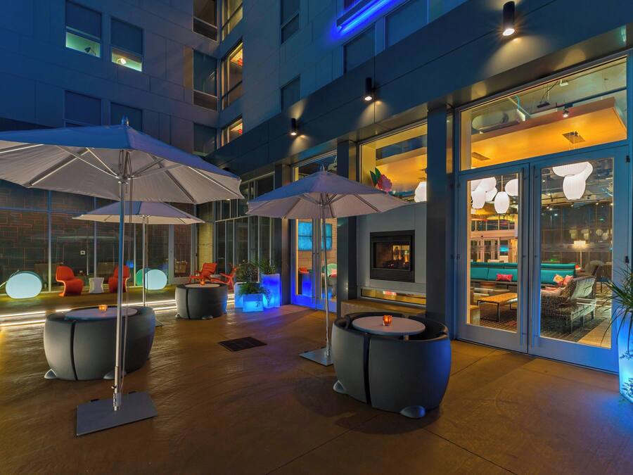 Een terras met parasols, ronde tafels en stoelen.