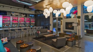 A modern bar area with a bar counter, seating, and a fireplace. - Aloft by Marriott College Station (College Station)