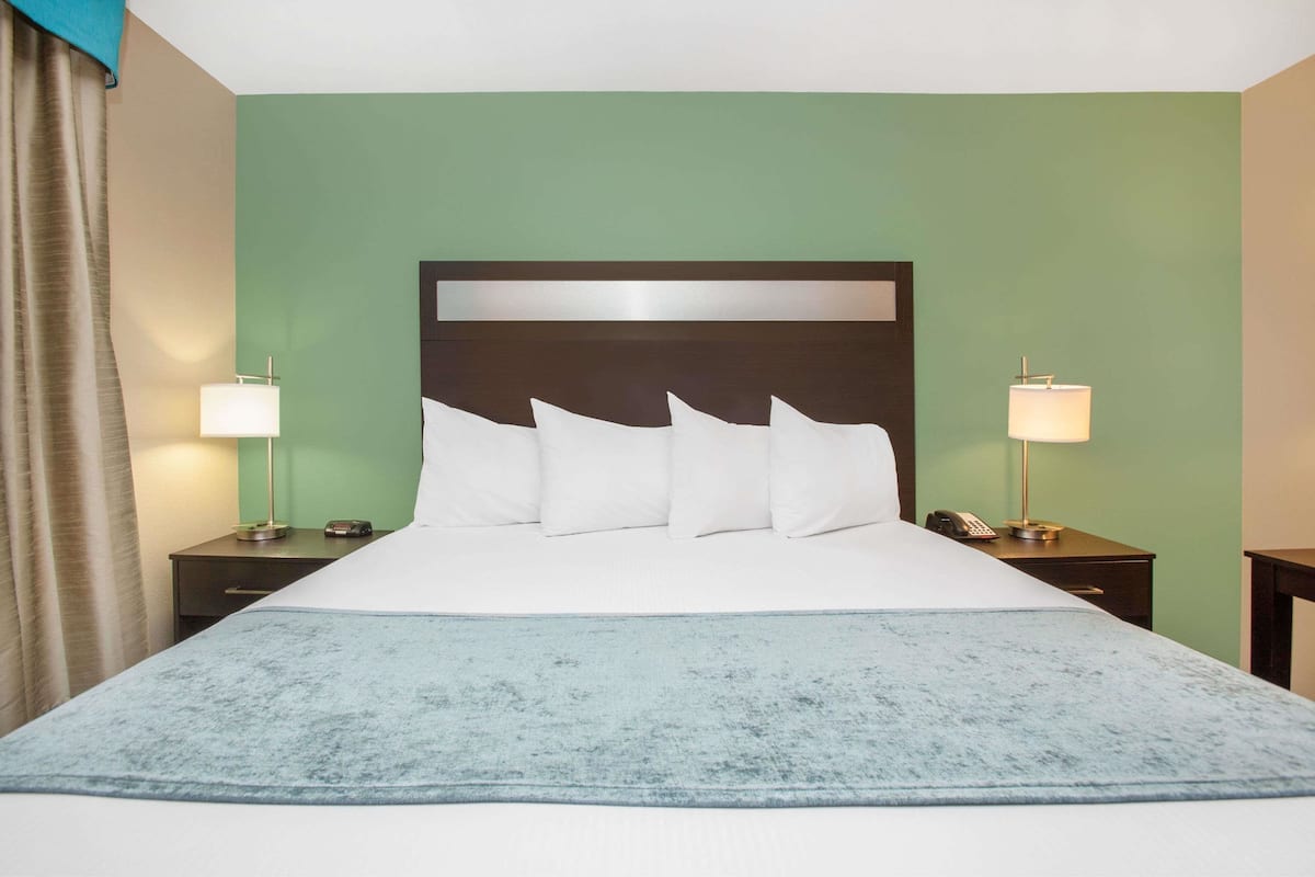 Ein Hotelzimmer mit einem großen Bett, zwei Nachttischen, einer Lampe und einem Vorhang.