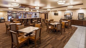A hotel lobby with multiple dining tables and chairs, a reception area, and a kitchen visible in the background. - Best Western Plus Lincoln Inn & Suites (Lincoln)