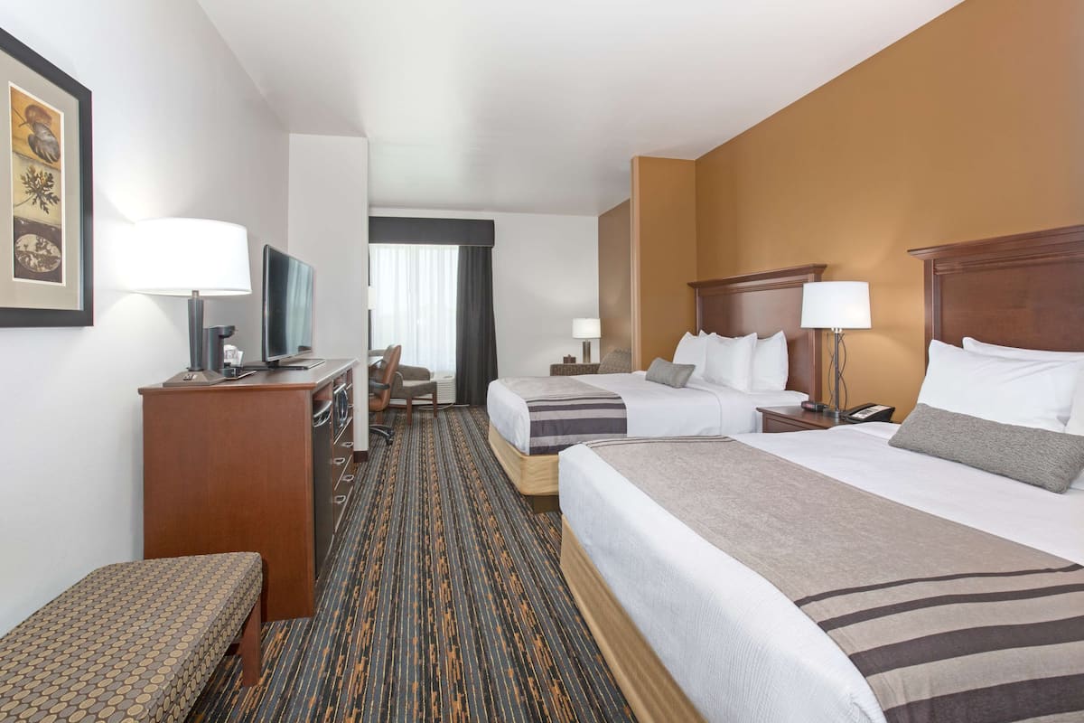 Une chambre d’hôtel avec deux lits, un bureau, une chaise et un petit coin salon.