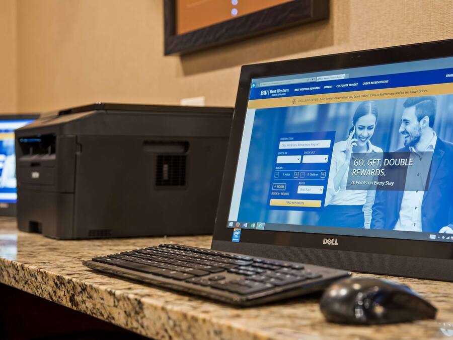 Una reception hotel con un computer che mostra un'interfaccia di prenotazione.