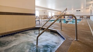 A hot tub area with a metal ladder, tiled walls, and a pool in the background. - Best Western Plus Lincoln Inn & Suites (Lincoln)