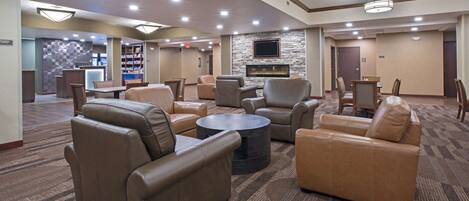 A spacious lobby with leather sofas, a coffee table, and a stone fireplace.