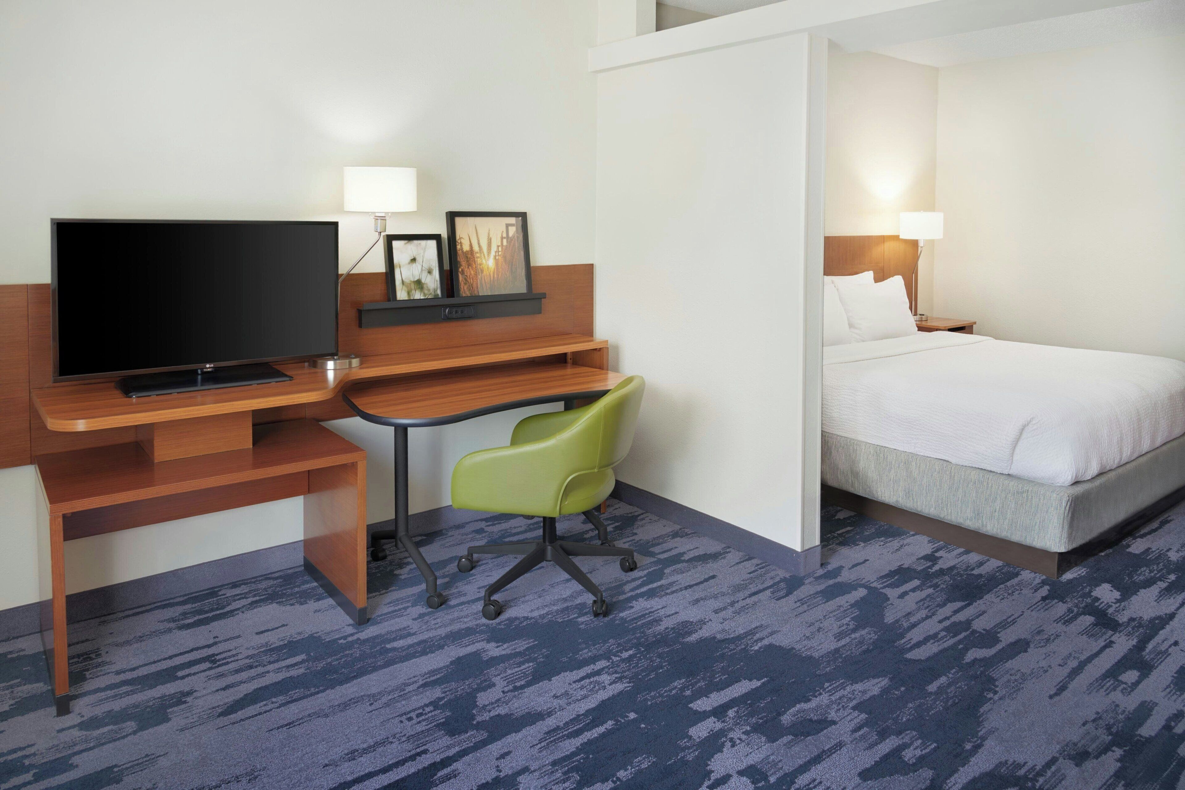 Ein Hotelzimmer mit Bett, Schreibtisch, Fernseher, Stuhl und Lampe.