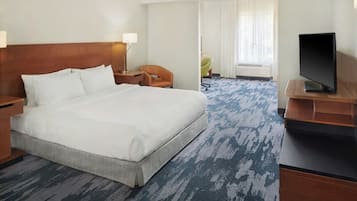 Una habitación de hotel con una cama grande, televisión, escritorio y una silla.