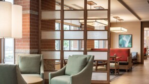 A modern interior with a seating area featuring cushioned chairs and a wooden table. - Hyatt Place Kansas City/Lenexa City Center (Lenexa)