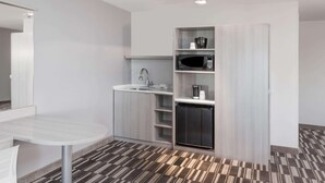 A compact kitchenette with a microwave, sink, and storage shelves. - Microtel Inn & Suites by Wyndham West Fargo Medical Center (West Fargo)