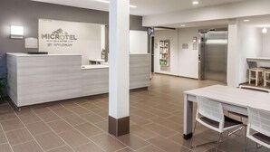 A modern hotel reception area with a reception desk, a waiting area, and a visible elevator. - Microtel Inn & Suites by Wyndham West Fargo Medical Center (West Fargo)