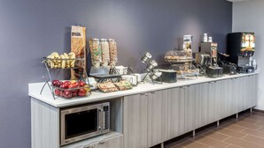 A buffet setup with various food items and a microwave. - Microtel Inn & Suites by Wyndham West Fargo Medical Center (West Fargo)