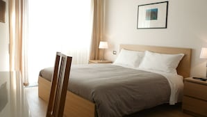 A hotel room with a bed, a wooden nightstand, a desk, and a chair. - Atticoromantica (Rome)