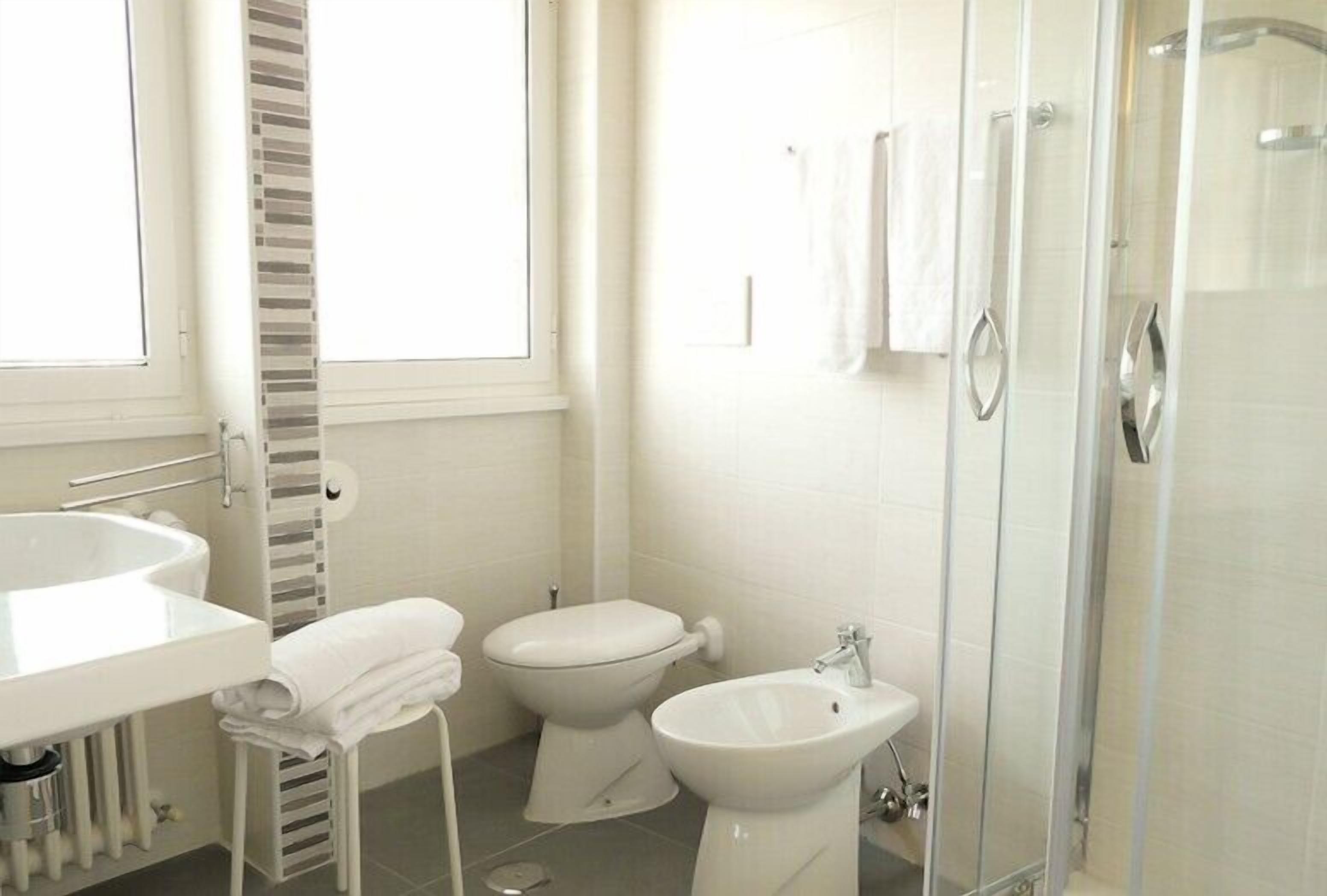 Une salle de bain moderne avec une douche à parois de verre, un lavabo blanc et des toilettes.