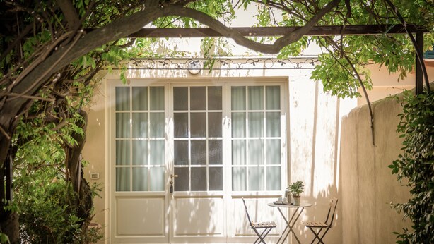 A small patio with a white door, a table with a chair, and a potted plant. - Villino Fiorentino (Florence)