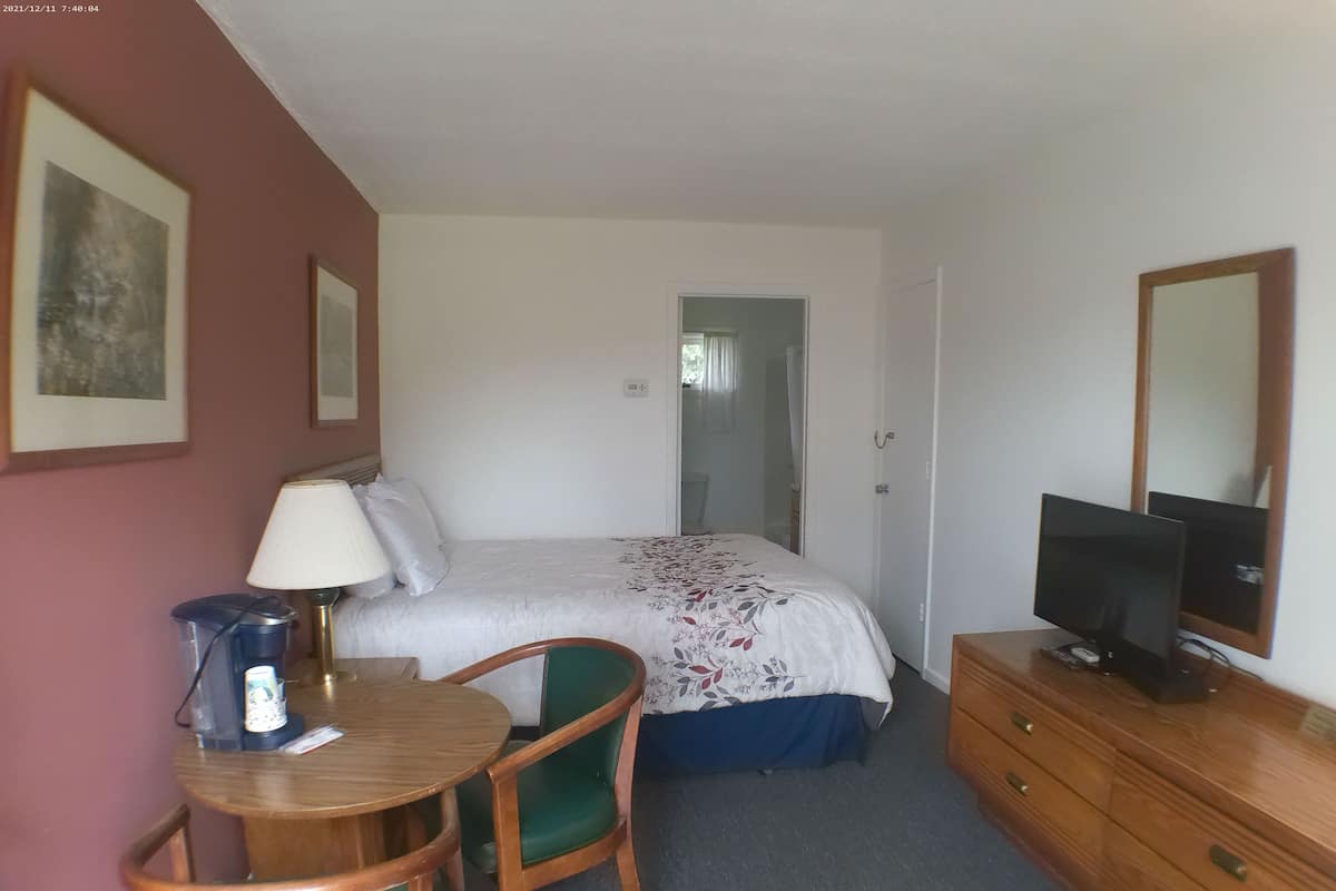 Une chambre d’hôtel comprenant un lit, un bureau avec une chaise, une télévision et une commode.