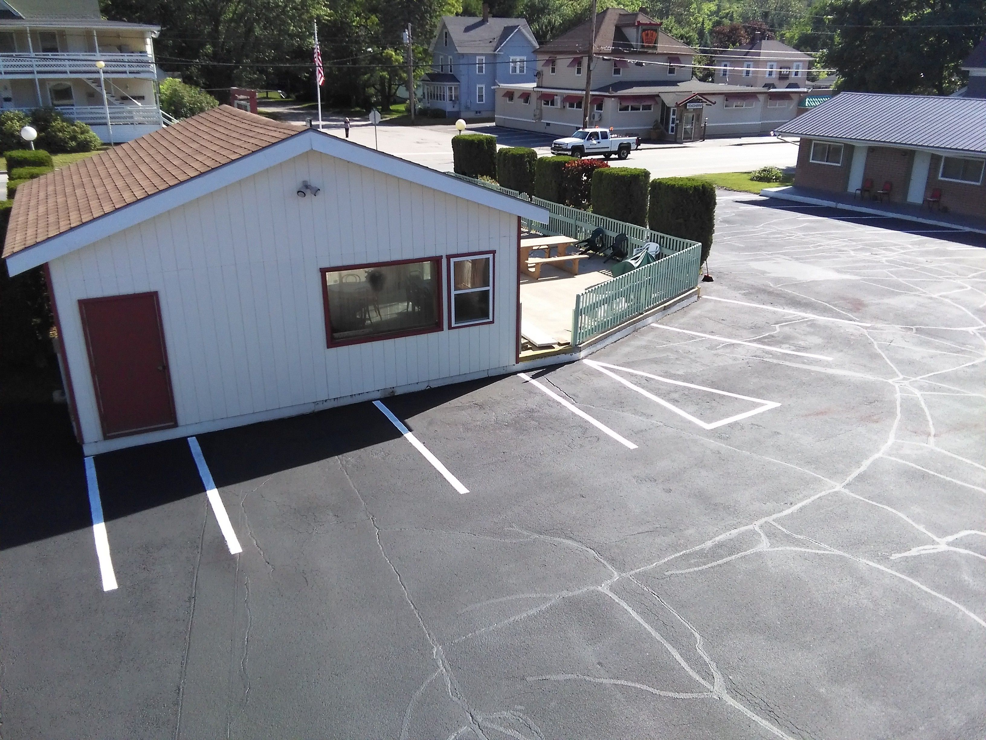 A small, single-story building with a red door and windows, adjacent to a parking lot with marked spaces.