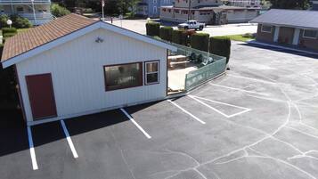 A small, single-story building with a red door and windows, adjacent to a parking lot with marked spaces.