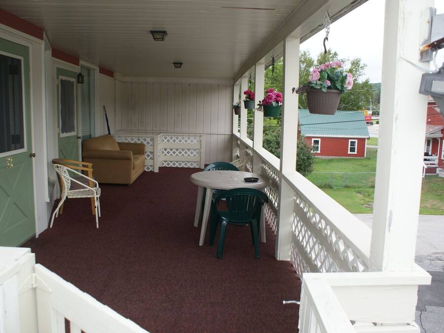 A covered porch with a green door, a brown sofa, and a small table with chairs.