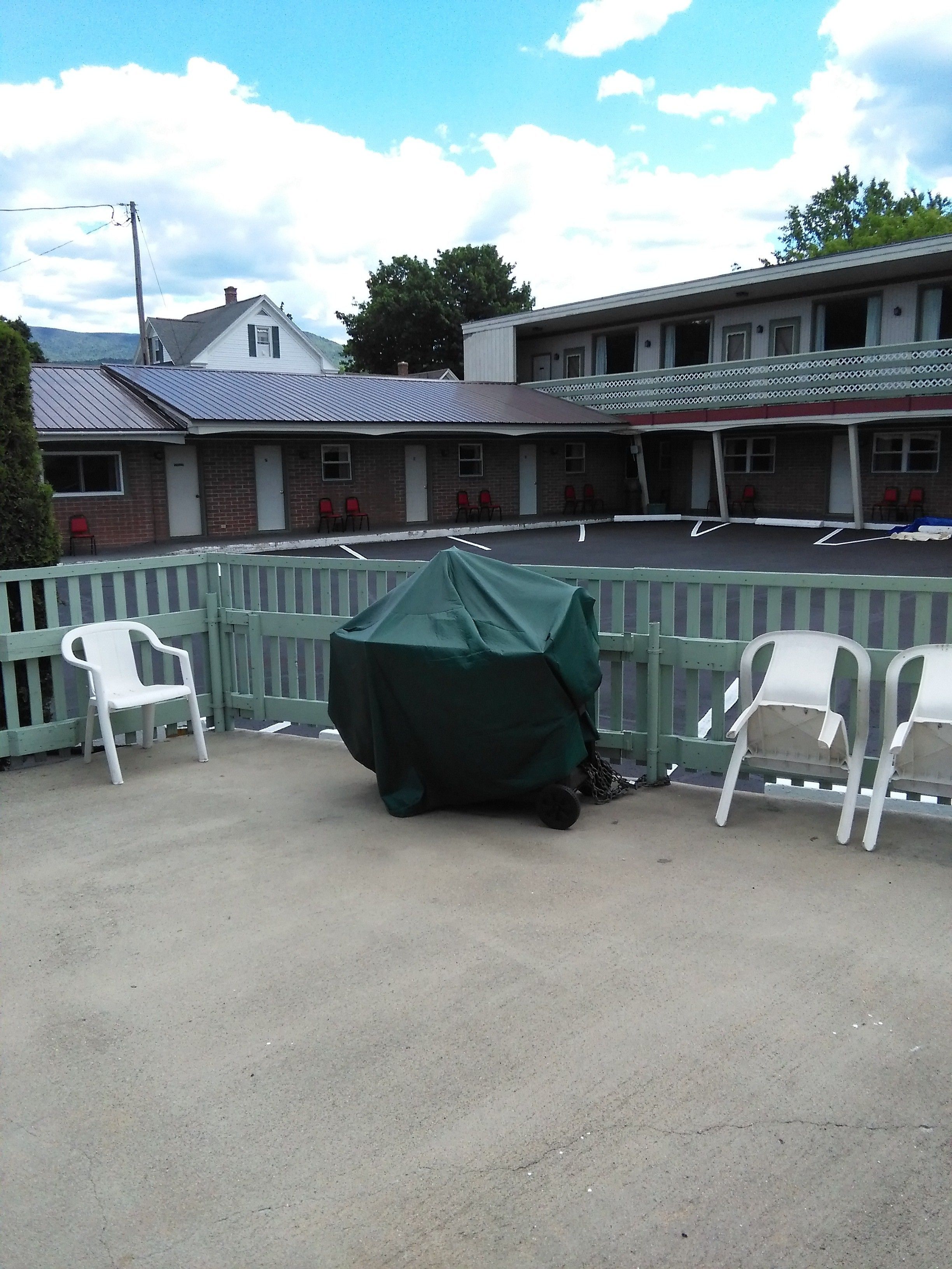 A building with a brick facade, multiple doors, and a covered outdoor seating area with chairs.
