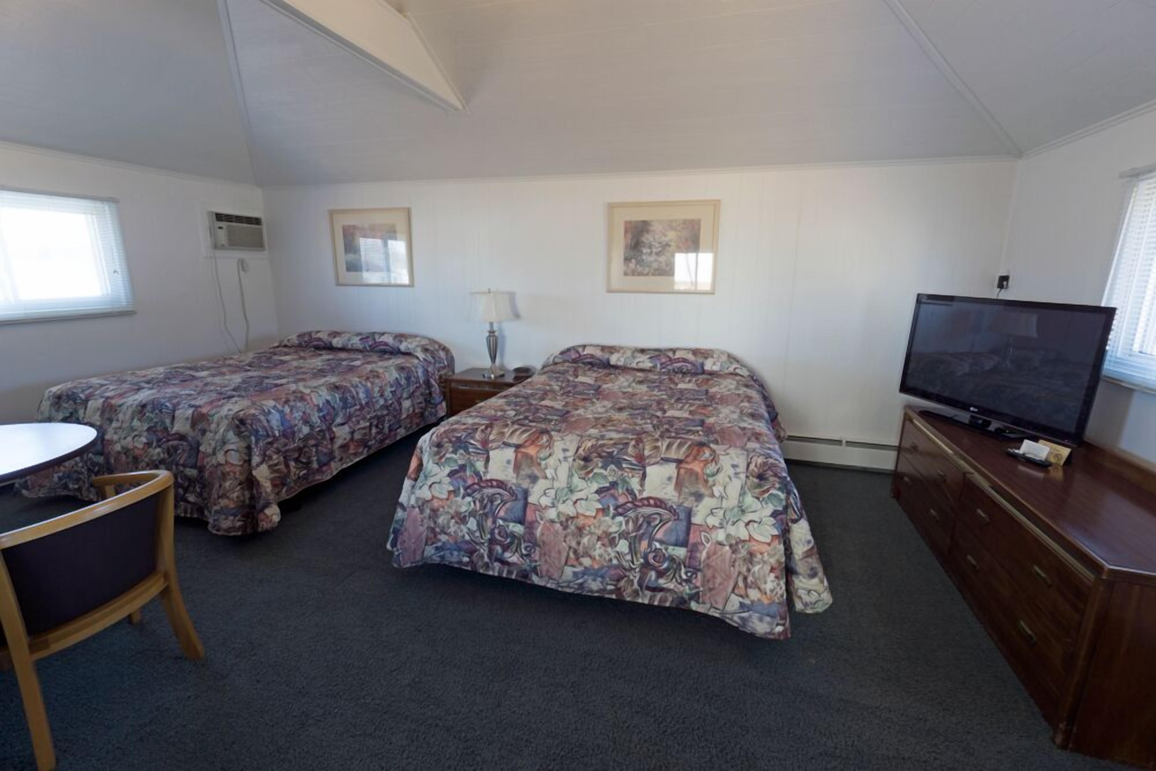 Une chambre avec deux lits, une télévision, un bureau et une chaise.