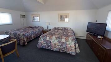 Une chambre avec deux lits, une télévision, un bureau et une chaise.