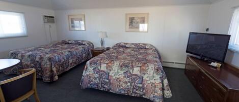 A bedroom with two beds, a TV, a desk, and a chair.