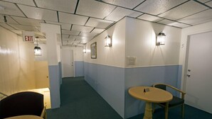 Un pasillo con una señal de salida, una mesa con una silla y una puerta marcada con el número 5.