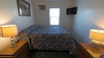 Una camera da letto con un letto, due comodini con lampade, una finestra, una TV a parete e un quadro incorniciato.