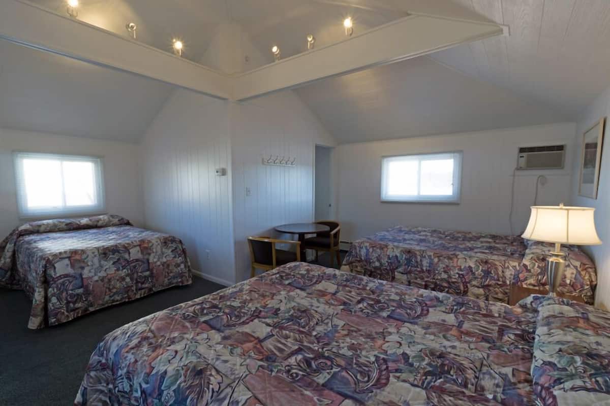 Une chambre avec deux lits, une petite table et une lampe.