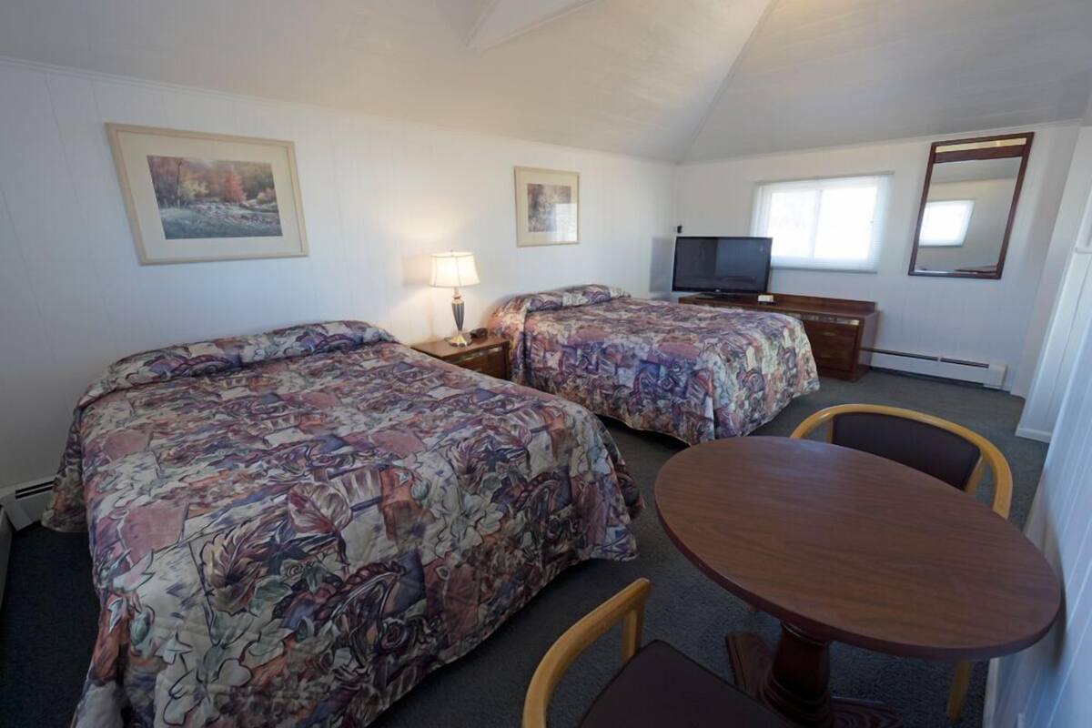 Une chambre d’hôtel avec deux lits, une télévision, un bureau et une table ronde.