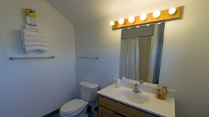 Un baño con inodoro, lavabo, espejo y perchero para toallas.