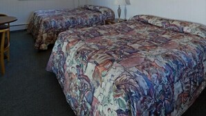 Habitación de motel con dos camas, un escritorio, una lámpara y una ventana.