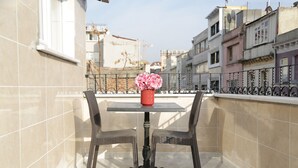 A balcony with a table and two chairs, a vase with flowers, and a view of buildings in the background. - Bayer Hotel (Istanbul)