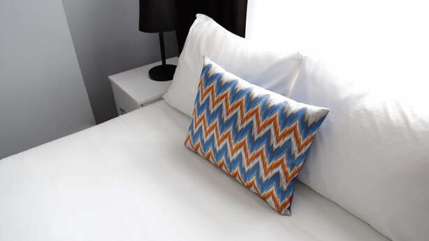 A neatly made bed with a white pillow and a patterned pillow. - Bayer Hotel (Istanbul)