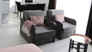 A modern living room with a grey sofa set, a small round table, and a dining area in the background. - Bayer Hotel (Istanbul)