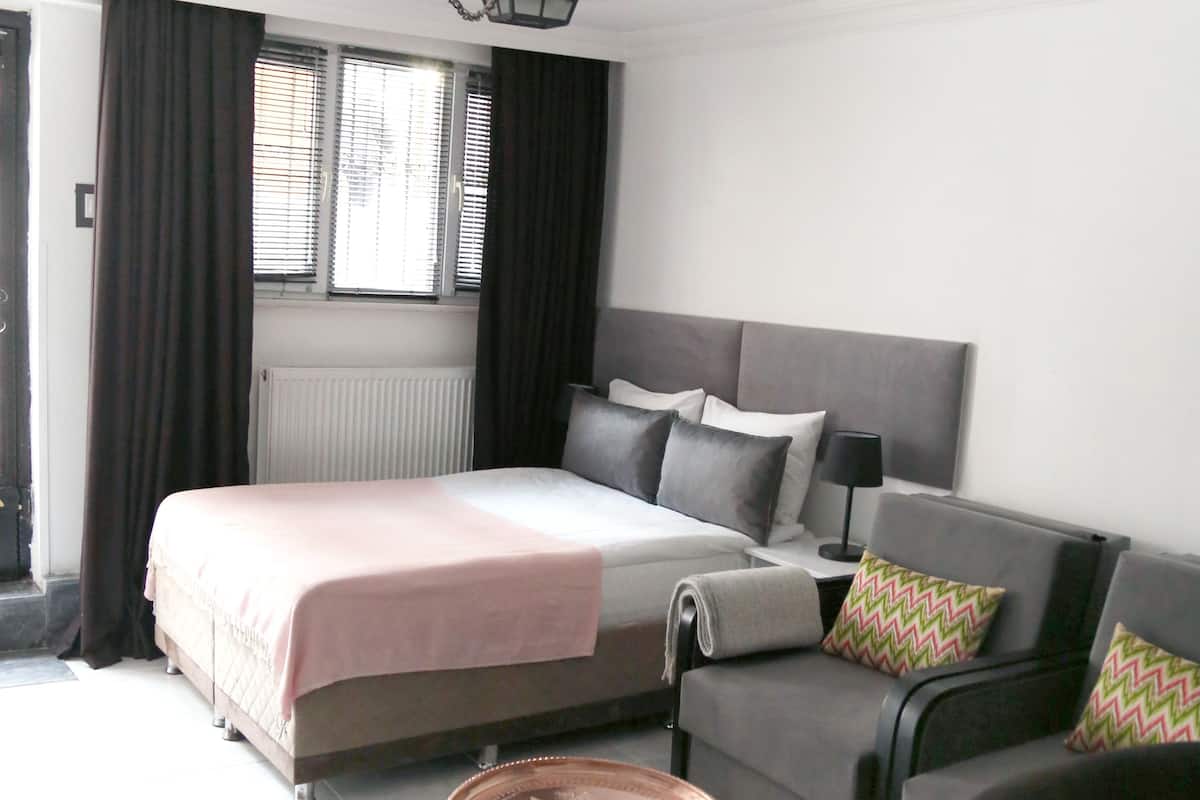 A bedroom with a bed, a sofa, a small round table, and a lamp.