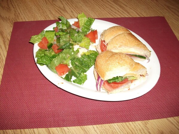 A plate with a sandwich and a salad on a table.